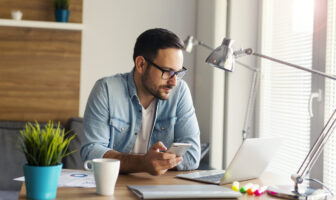 Junger Mann arbeitet zu Hause am Laptop im Homeoffice